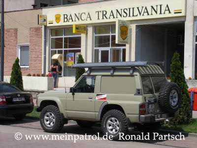 Fumosito und der Held vor der Banca Transilvania Transsylvania in Sebis Rumänien Nissan, nissan, Patrol, patrol, Safari, safari, Patrol GR, patrol gr, Safari GR, safari gr, GR, gr, KR, kr, Patrol GQ, patrol gq, Safari GQ, safari gq, GQ, gq, Y60, y60, JRY60, jry60, JRLY60, jrly60, VRGY60, vrgy60, ARGY60, argy60, TD42, td42, 4.2-Liter, 4.2 Litre, 4.2 litre, 4,2-Liter, Sechszylinder, Inlinesix, inlinesix, high roof, Hochdach, Jeep, jeep, Wrangler, wrangler, TJ, tj, Yamaha, Kodiak, yamaha, kodiak, 4x4, 4WD, 4wd, four wheel drive, AWD, awd, Offroad, offroad, Off Road, OFF ROAD, off road, offroader, Allradler, Allradantrieb, Geländeuntersetzung, Reduktion, low gears, Differenzialsperre, Differentialsperre, locker, Gelaendewagen, Geländewagen, Reisen, reisen, travel, Expedition, expedition, Tour, tour, Tuning, tuning, tune, Zubehör, equipment